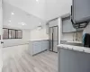 Kitchen with a wall unit AC, kitchen peninsula, sink, gray cabinetry, and stainless steel fridge