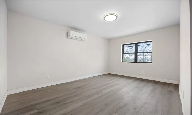 Unfurnished room with a wall mounted AC and light hardwood / wood-style floors