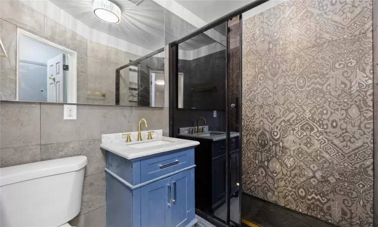 Bathroom with toilet, vanity, and tile walls