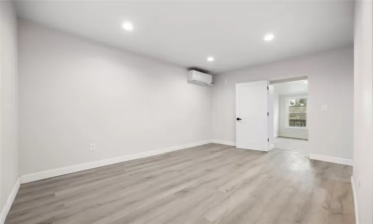 Unfurnished room with light hardwood / wood-style floors and a wall mounted AC