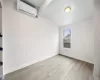 Unfurnished room with lofted ceiling with beams, a wall unit AC, and light wood-type flooring