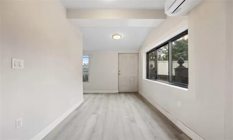 Hallway with light hardwood / wood-style flooring, lofted ceiling, and a wall mounted air conditioner