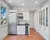 Kitchen featuring white cabinetry, backsplash, built in appliances, and wine cooler