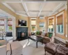 Living room with a wall mounted AC, beam ceiling, wood-type flooring, coffered ceiling, and ornamental molding