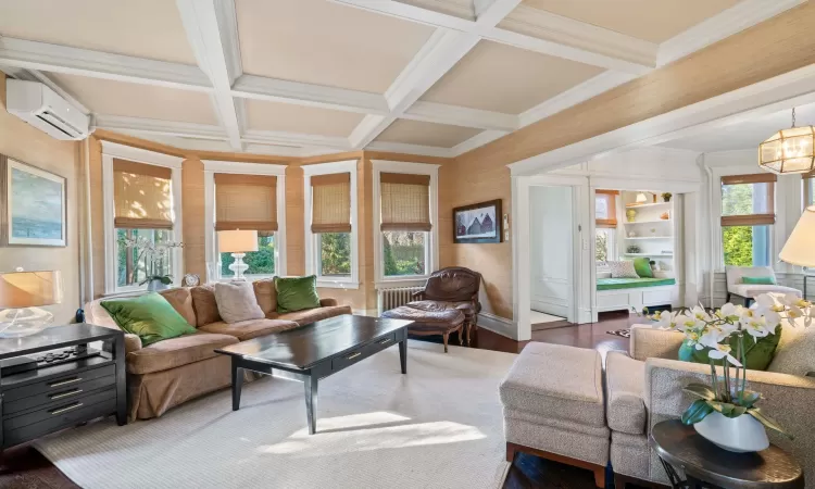 Living room with beam ceiling, coffered ceiling, a wall mounted air conditioner, dark wood-type flooring, and ornamental molding