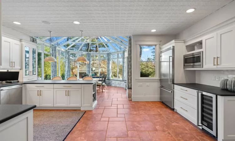 Kitchen featuring white cabinetry, pendant lighting, built in appliances, and wine cooler