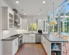 Kitchen with white cabinetry, a breakfast bar area, appliances with stainless steel finishes, wall chimney range hood, and pendant lighting