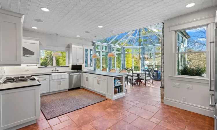 Kitchen featuring white cabinets, appliances with stainless steel finishes, a healthy amount of sunlight, and pendant lighting