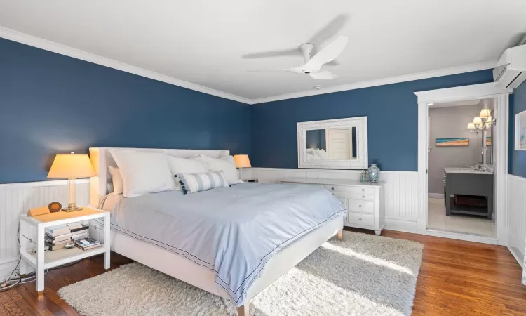 Bedroom featuring a wall unit AC, ceiling fan, crown molding, and dark hardwood / wood-style floors