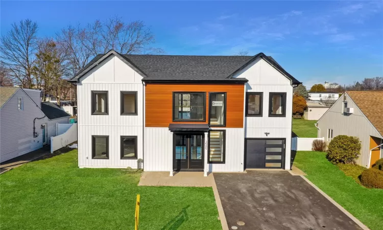 View of front facade featuring a garage, a front lawn, and french doors