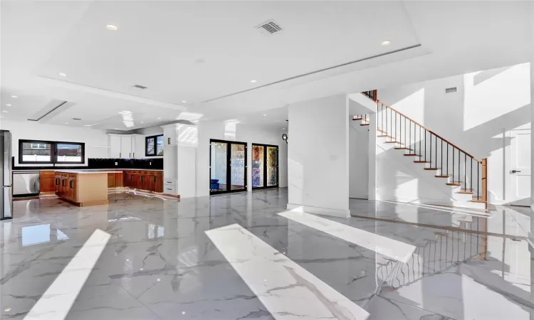 Kitchen featuring stainless steel fridge with ice dispenser, white cabinetry, a raised ceiling, and a kitchen island