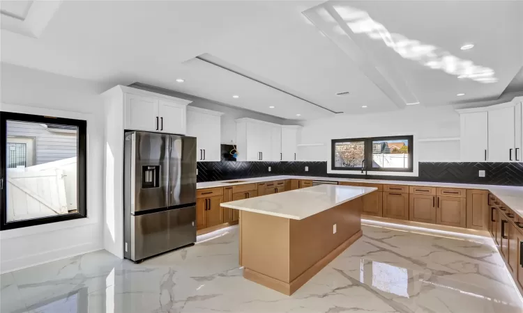 Kitchen with stainless steel appliances, decorative backsplash, plenty of natural light, white cabinets, and a center island