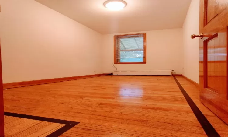 Spare room featuring light wood-type flooring and a baseboard radiator