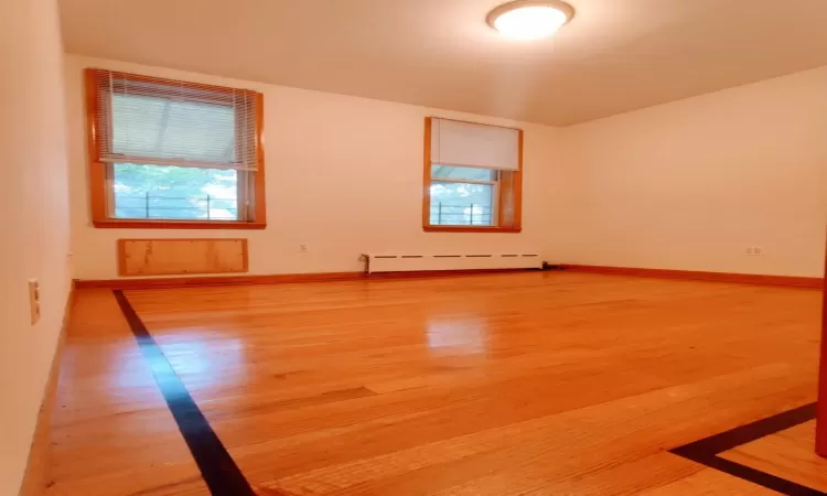 Spare room with a baseboard radiator and hardwood / wood-style floors