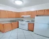 Kitchen featuring light tile patterned floors, sink, light brown cabinets, and white appliances