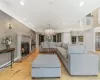 Living room with a chandelier, light hardwood / wood-style floors, decorative columns, and ornamental molding