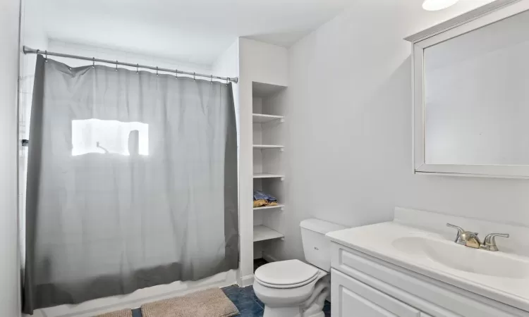 Full bathroom with toilet, tile patterned floors, shower / tub combo with curtain, and vanity