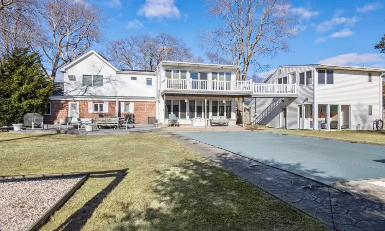 Back of house featuring a pool side deck, a balcony, a patio, and a lawn