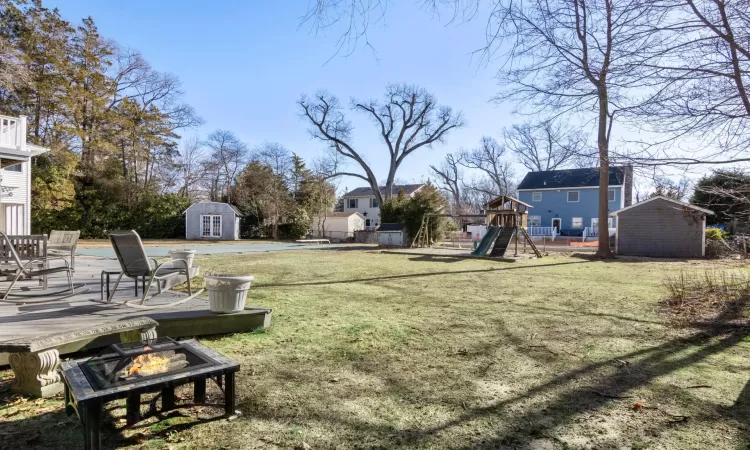 View of yard with an outdoor fire pit, a playground, and a shed