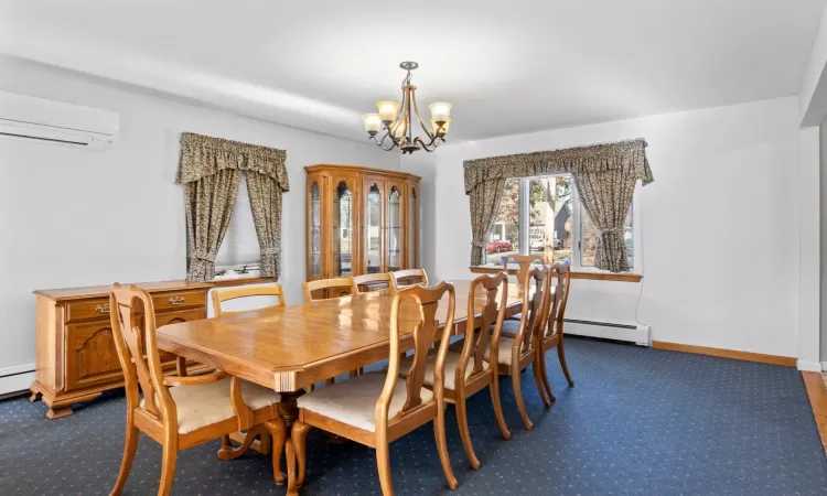 Carpeted dining area featuring a notable chandelier, a wall unit AC, and a baseboard heating unit