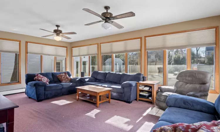 Living room with ceiling fan, a baseboard radiator, and light carpet