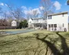 Rear view of house with a lawn, a covered pool, and a balcony