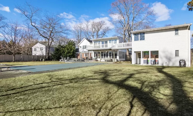 Rear view of house with a lawn, a covered pool, and a balcony