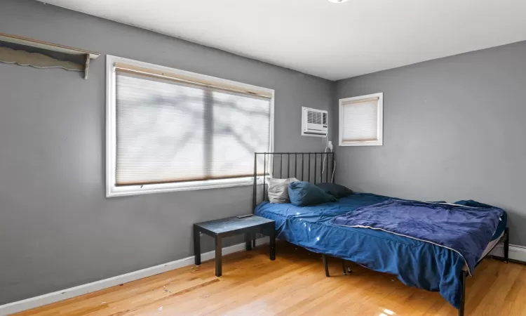 Bedroom featuring a wall unit AC and hardwood / wood-style floors