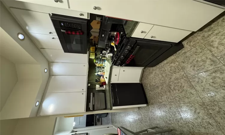 Kitchen with backsplash, stove, dishwasher, white cabinets, and sink