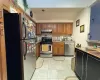 Kitchen with tasteful backsplash, light tile patterned floors, and appliances with stainless steel finishes