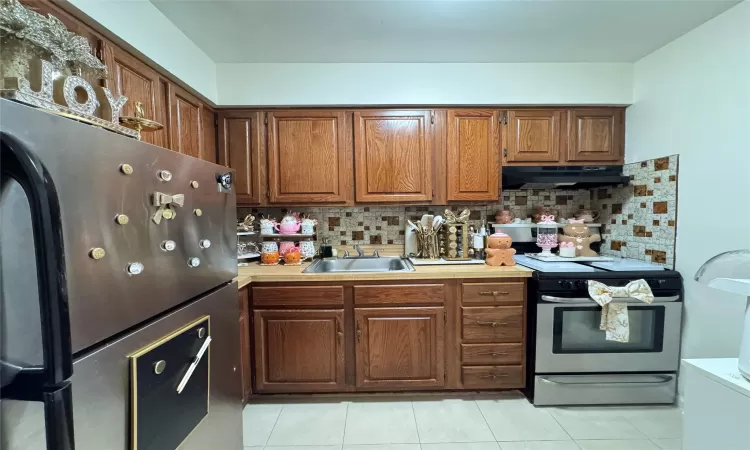 Kitchen featuring light tile patterned floors, appliances with stainless steel finishes, tasteful backsplash, and sink