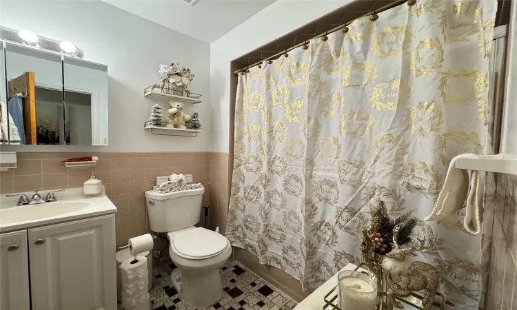 Bathroom with toilet, tile walls, walk in shower, and vanity