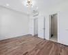 Unfurnished bedroom with a wall mounted AC, light hardwood / wood-style floors, and a notable chandelier