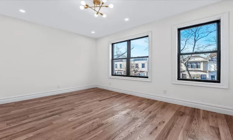 Empty room with wood-type flooring and an inviting chandelier