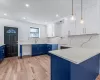 Kitchen featuring blue cabinetry, pendant lighting, white cabinets, and tasteful backsplash