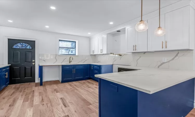 Kitchen featuring blue cabinetry, pendant lighting, white cabinets, and tasteful backsplash