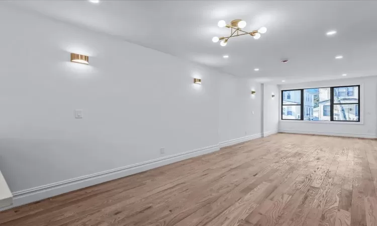 Unfurnished room featuring a chandelier and light wood-type flooring