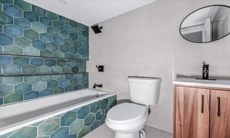 Full bathroom featuring toilet, vanity, tile walls, and tiled shower / bath