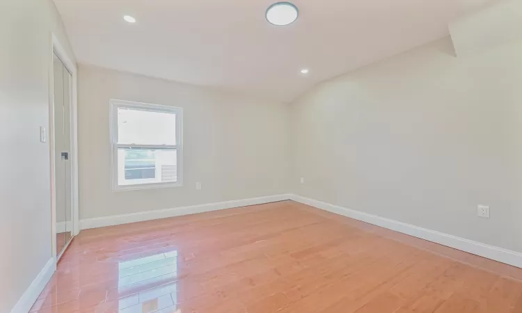 Unfurnished room with light hardwood / wood-style floors and lofted ceiling