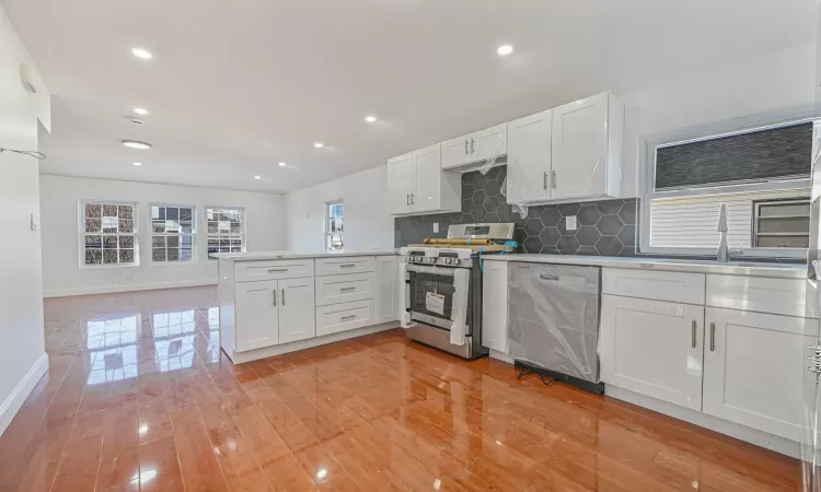 Kitchen with sink, white cabinetry, appliances with stainless steel finishes, and kitchen peninsula