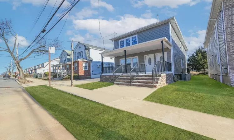 View of front of property featuring covered porch and a front yard