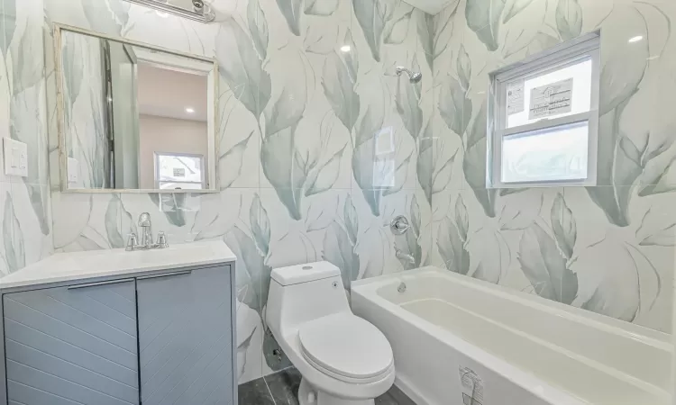 Full bathroom with toilet, a wealth of natural light, tile walls, and vanity