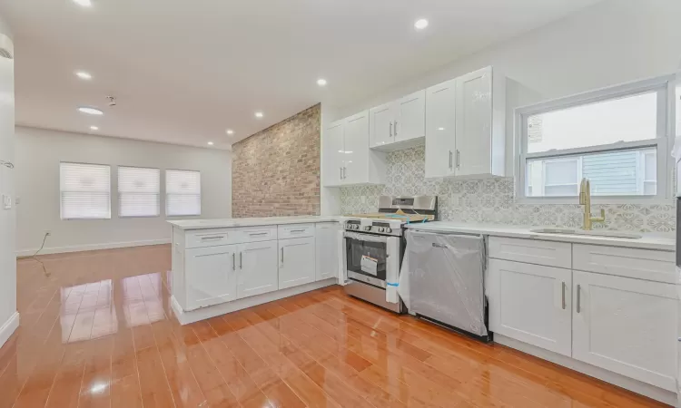 Kitchen with appliances with stainless steel finishes, white cabinetry, sink, backsplash, and kitchen peninsula