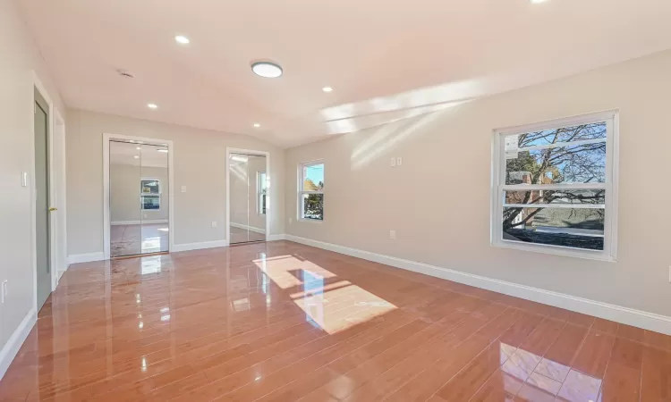 Spare room featuring plenty of natural light, wood-type flooring, and vaulted ceiling