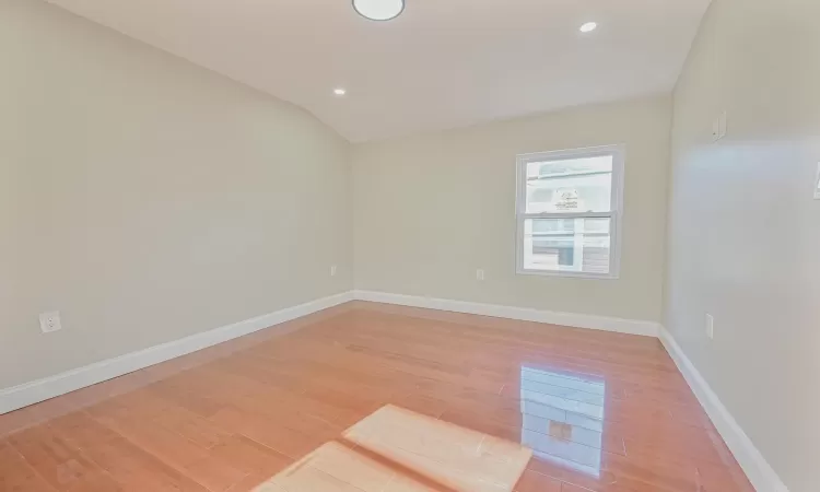 Unfurnished room with light wood-type flooring and vaulted ceiling