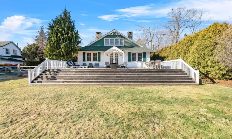 Back of property with a wooden deck and a lawn