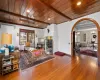 Living room with wood ceiling, wood-type flooring, an inviting chandelier, a wall unit AC, and beam ceiling