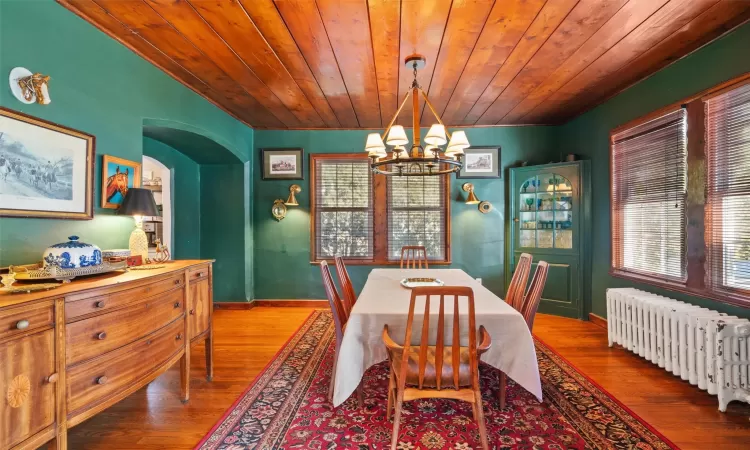 Dining room with radiator, wooden ceiling, wood-type flooring, and a notable chandelier