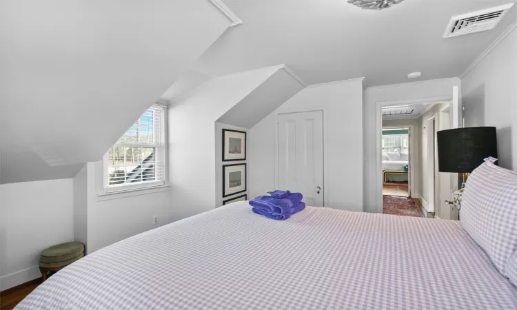 Bedroom with vaulted ceiling, ornamental molding, dark hardwood / wood-style flooring, and multiple windows