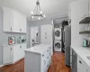 Kitchen featuring appliances with stainless steel finishes, stacked washer / dryer, white cabinetry, and decorative light fixtures